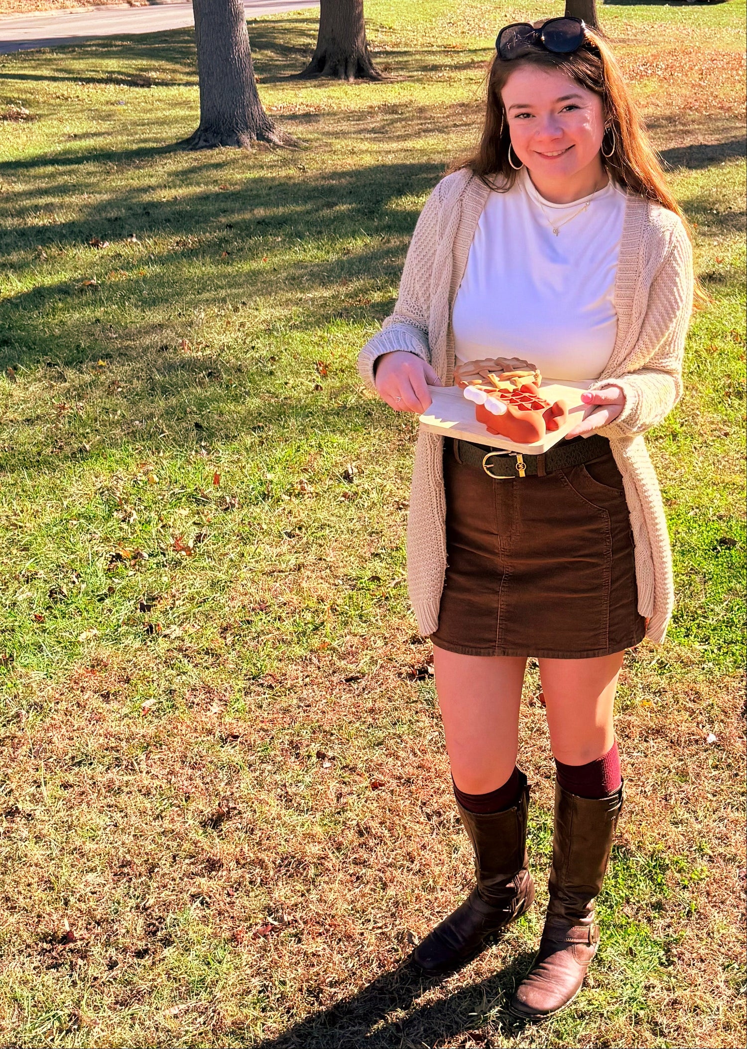 Woman wearing a skirt holding a platter of fake food outdoors